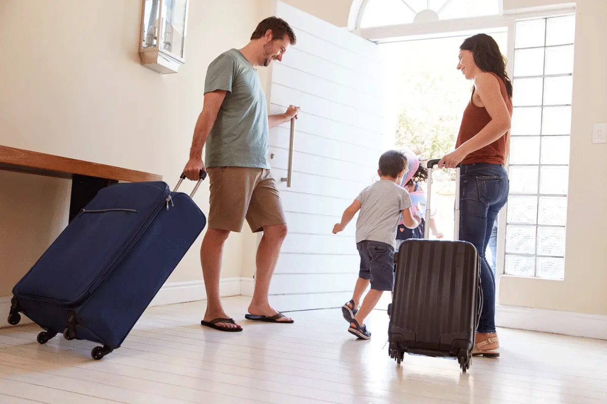 A family leaving the house with packed bags